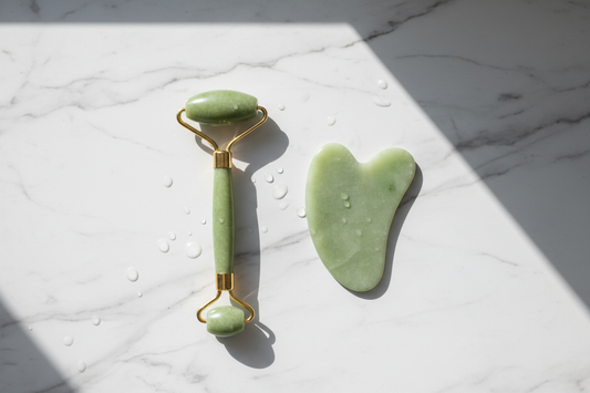 "Natural jade roller and gua sha tool displayed separately on white marble surface, top view, professional product photography, soft natural lighting" 